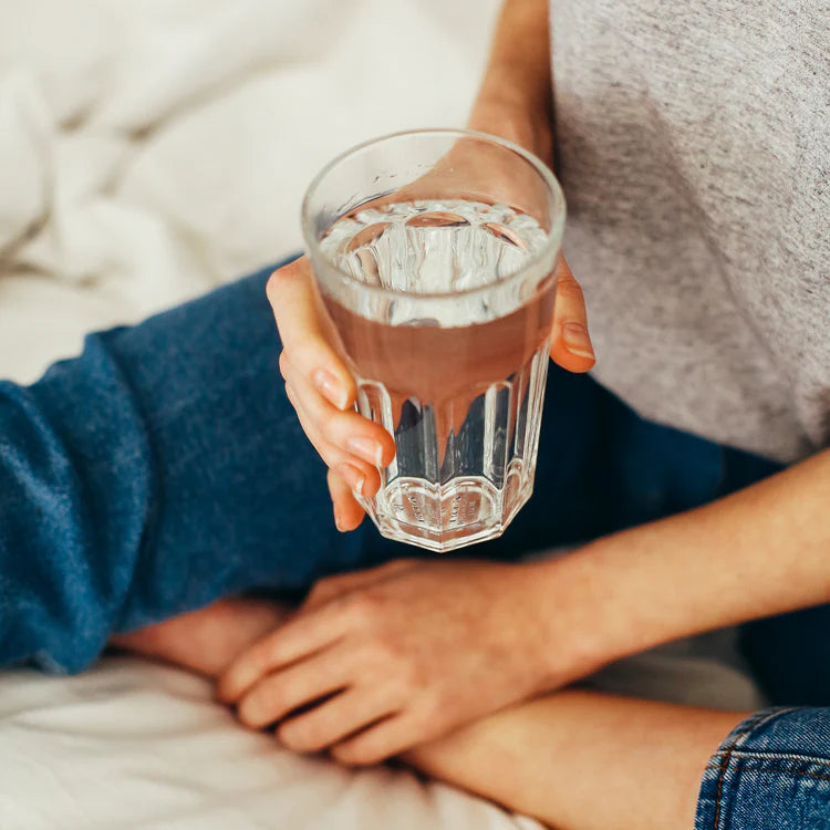 Person holding a glass of water, muscimol isolate drink enhancer